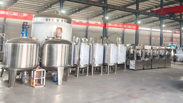 Factory workshop view of full liquid detergent production line, stainless steel mixing tanks and automatic bottle filling equipment for liquid soap